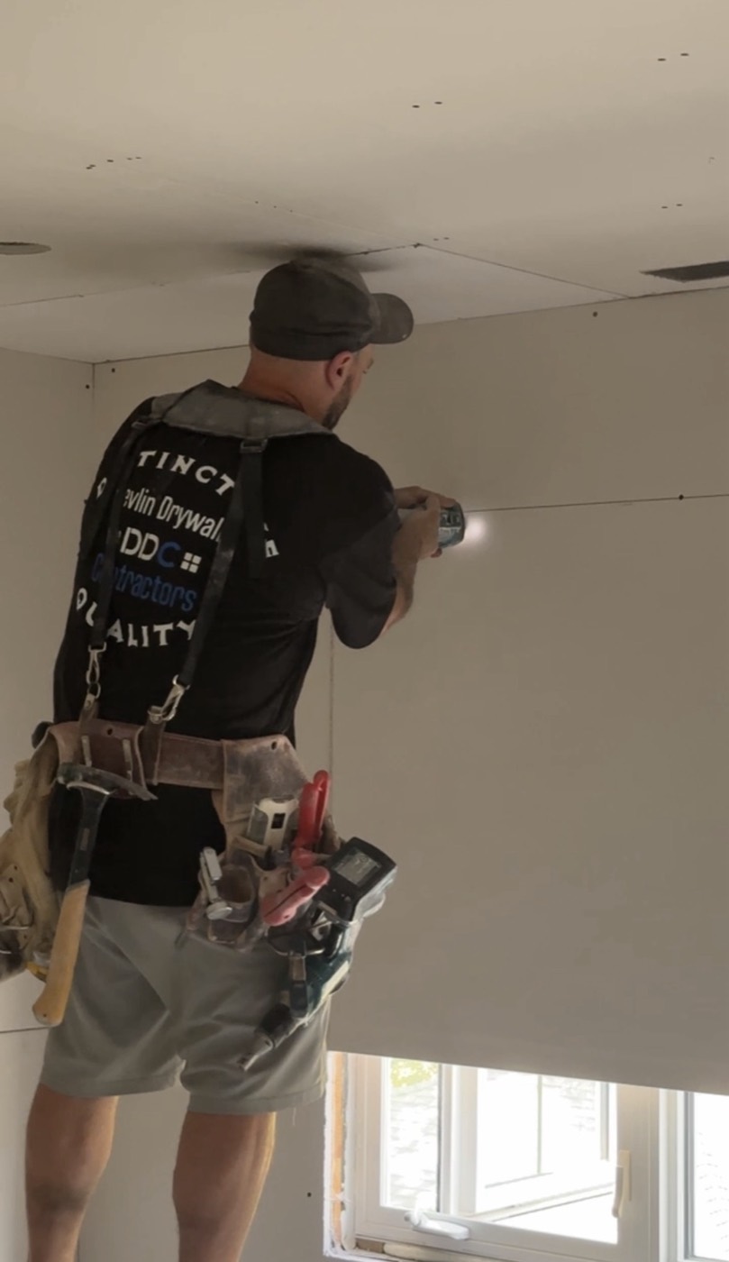 Devlin Drywall installer fastening a ceiling board on a Lower Mainland renovation